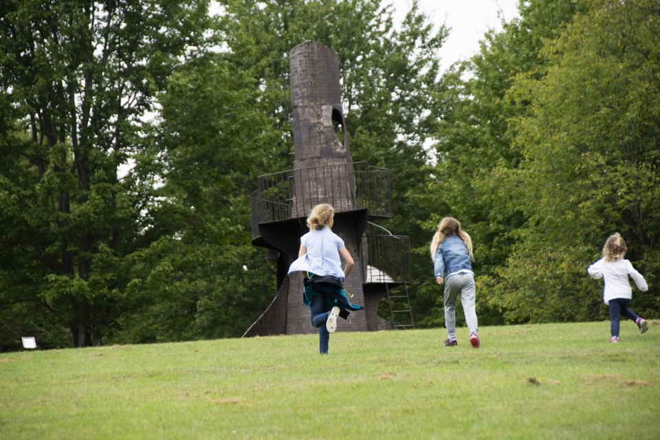 Kids running to tower sculpture