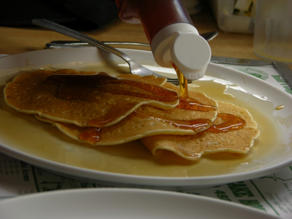 Maple syrup being poured on pancakes at Moore's Pancake House